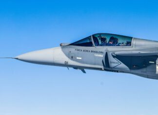 Trump é bom para negócios, diz fabricante do caça Gripen – 27/03/2026 – Mundo Aeronave de caça F-5 da Força Aérea Brasileira voa em céu claro. Piloto visível na cabine com capacete e equipamentos de voo.